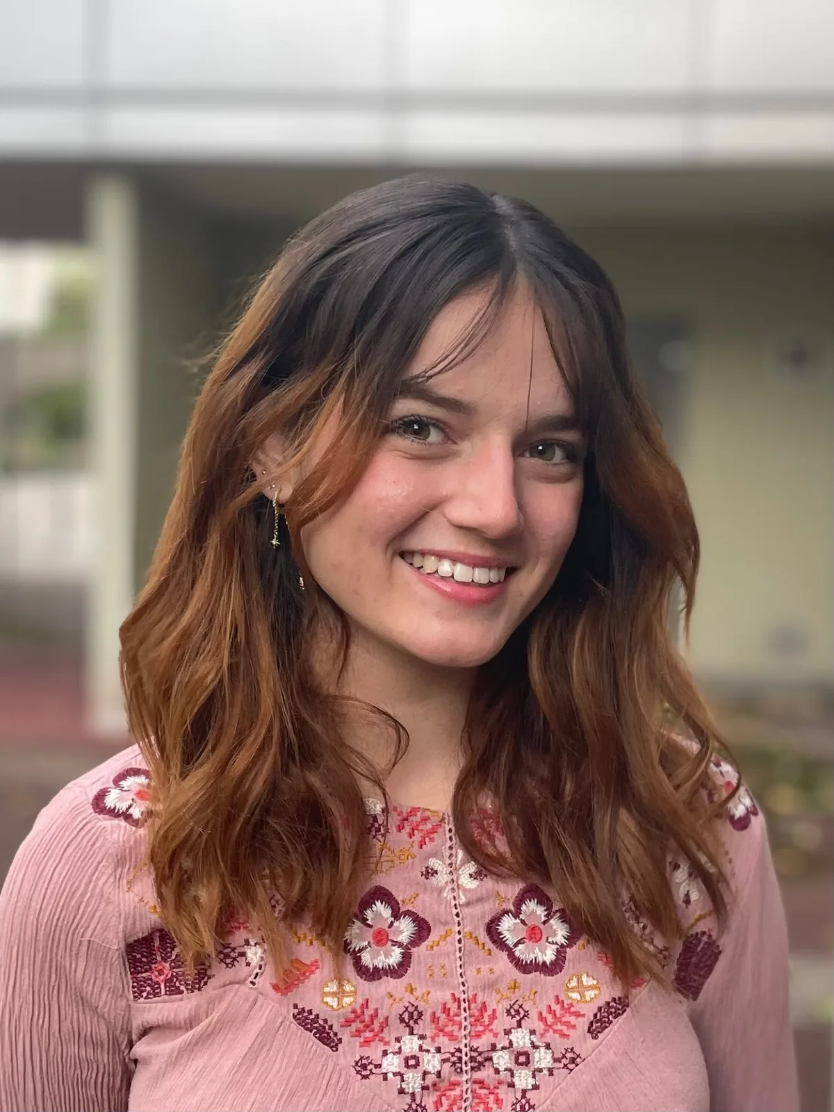 Portrait de Celia Bruneel, souriante, en blouse rose brodée